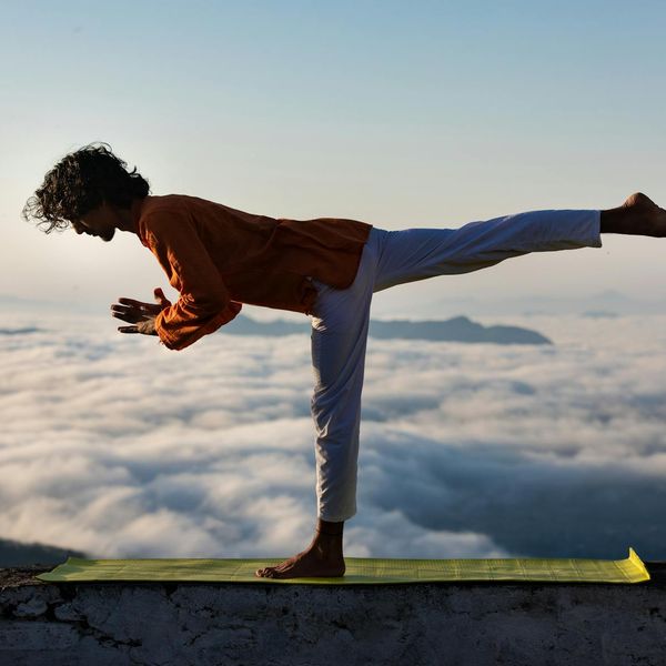 Man stretching peacefully outdoors at sunrise.